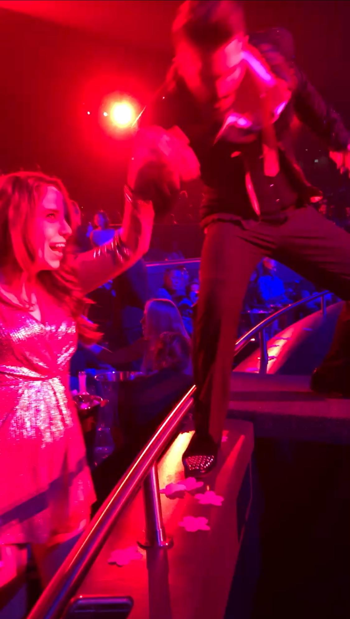 A person and person dancing in a concert

Description automatically generated