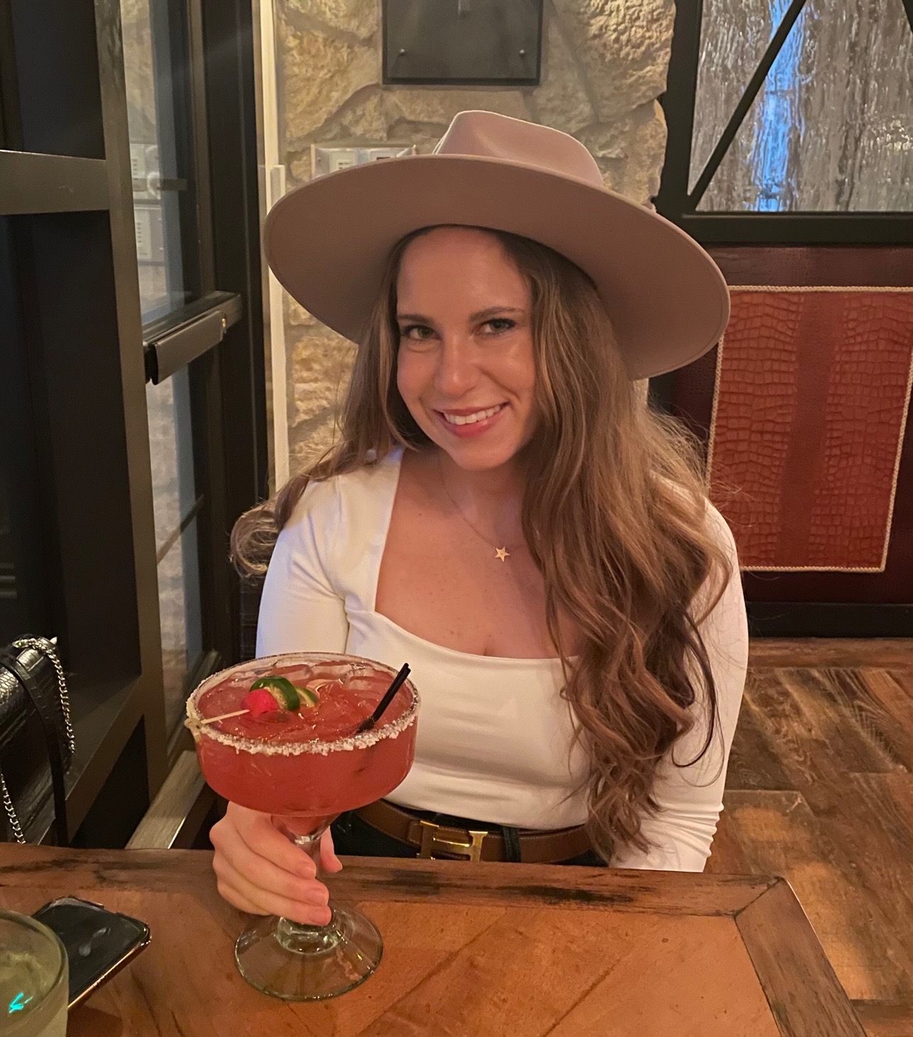A person wearing a hat and holding a drink

Description automatically generated