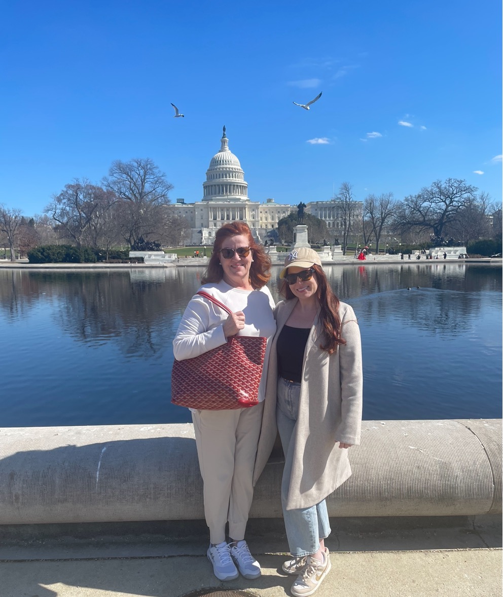 Two women standing next to each other in front of a body of water

Description automatically generated