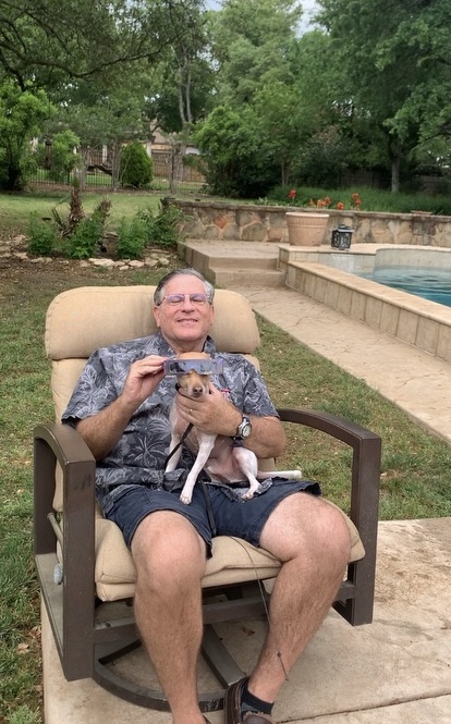 A person sitting in a chair holding a dog
Description automatically generated