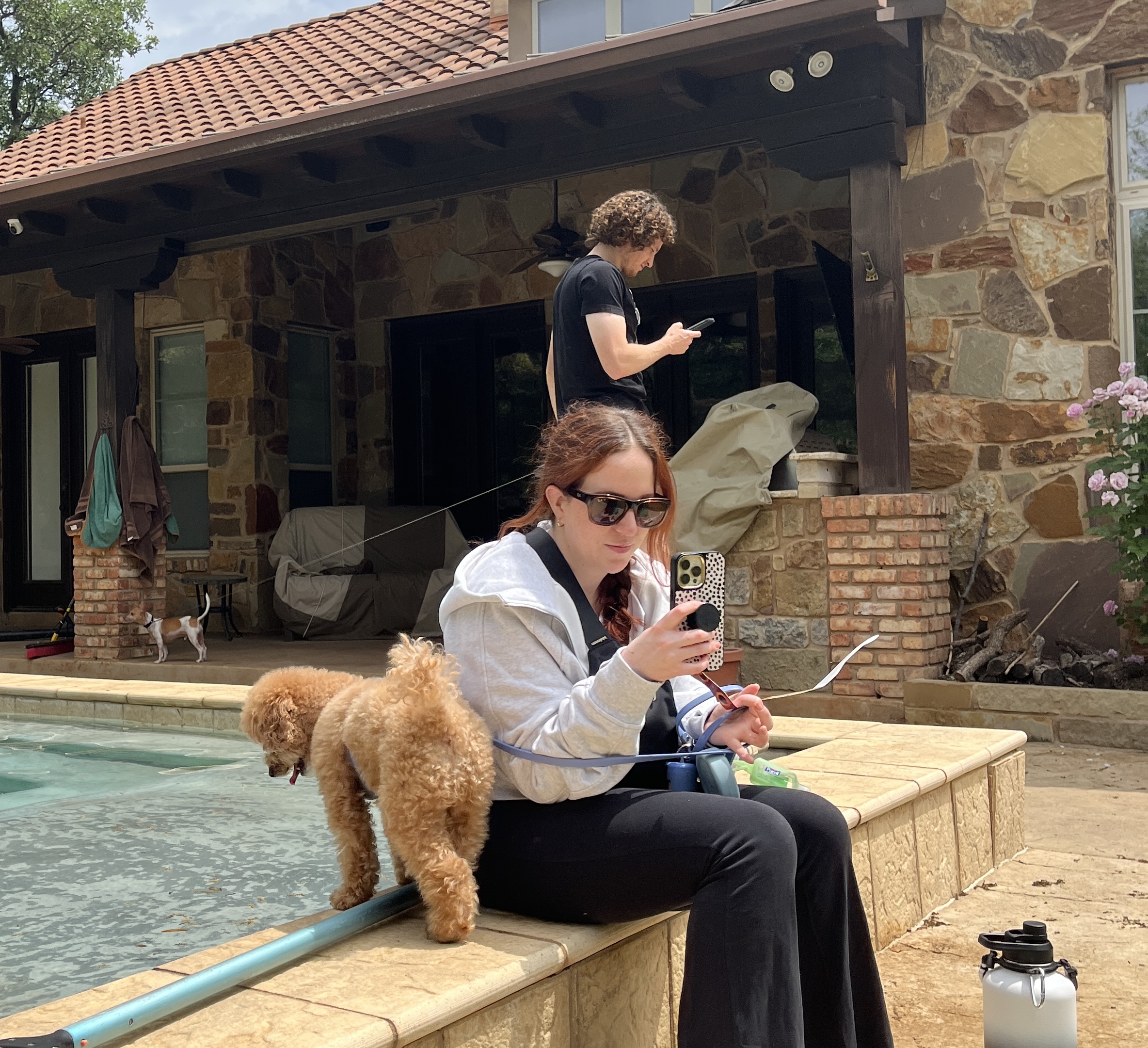 A person sitting on a ledge with a dog by her
Description automatically generated