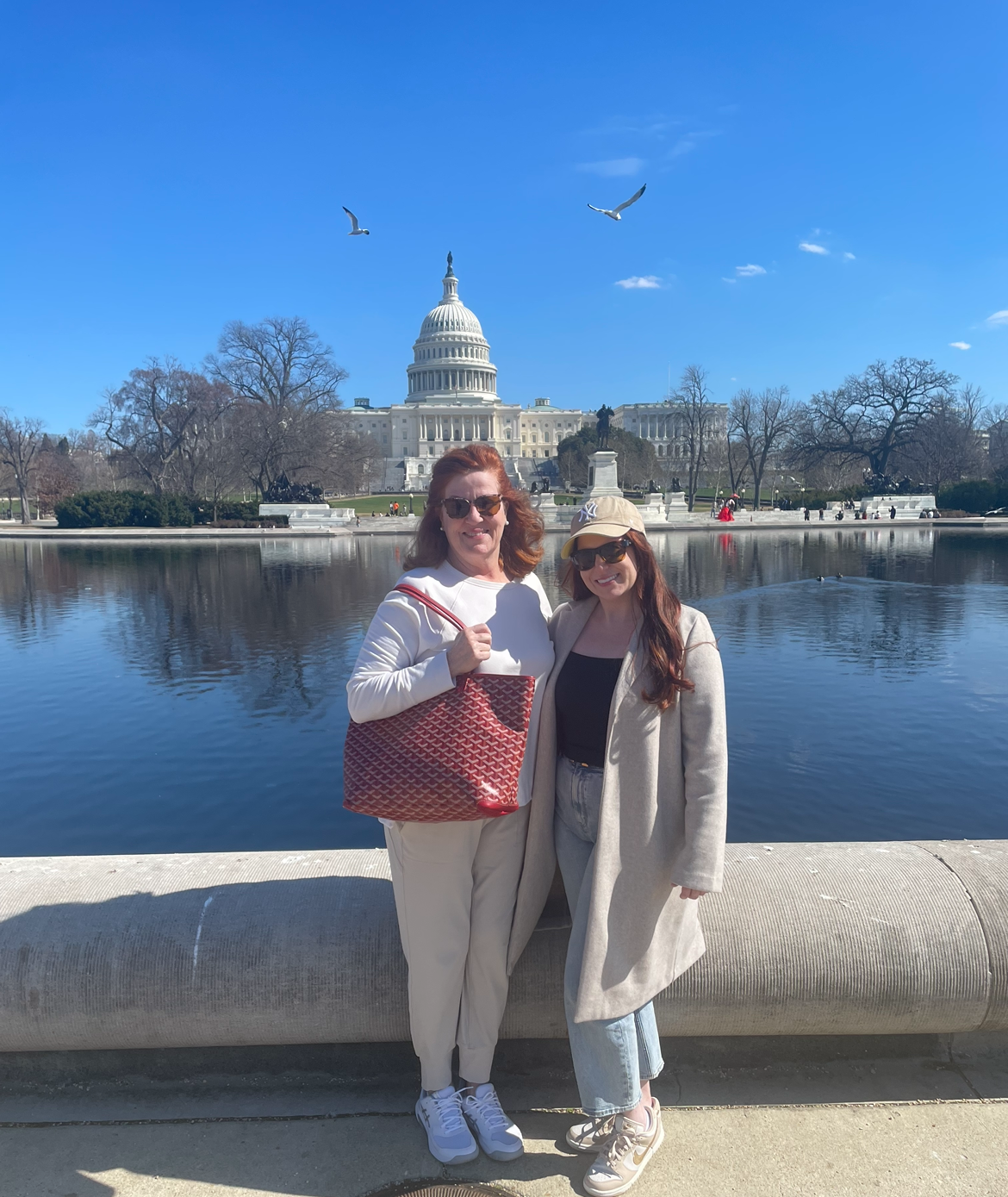 Two women standing next to each other in front of a body of water

Description automatically generated